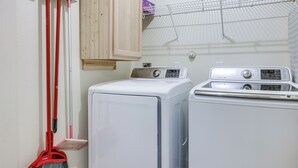 Ein Waschbereich mit Waschmaschine und Trockner, einem Mopp und einem Schrank.
