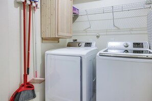 Ein Waschbereich mit Waschmaschine und Trockner, einem Mopp und einem Schrank.