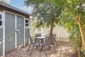 Eine Terrasse mit Tisch und Stühlen, ein Holzzaun und ein Baum.