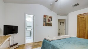 Ein Schlafzimmer mit einem Bett, einem Fernseher, einem Holzschrank und einer Tür zu einem Badezimmer.