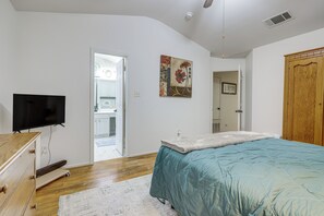 Ein Schlafzimmer mit einem Bett, einem Fernseher, einem Holzschrank und einer Tür zu einem Badezimmer.