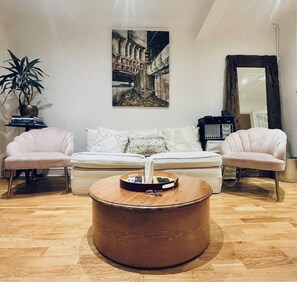 A modern living room with a sofa, two armchairs, a coffee table, and a painting on the wall.