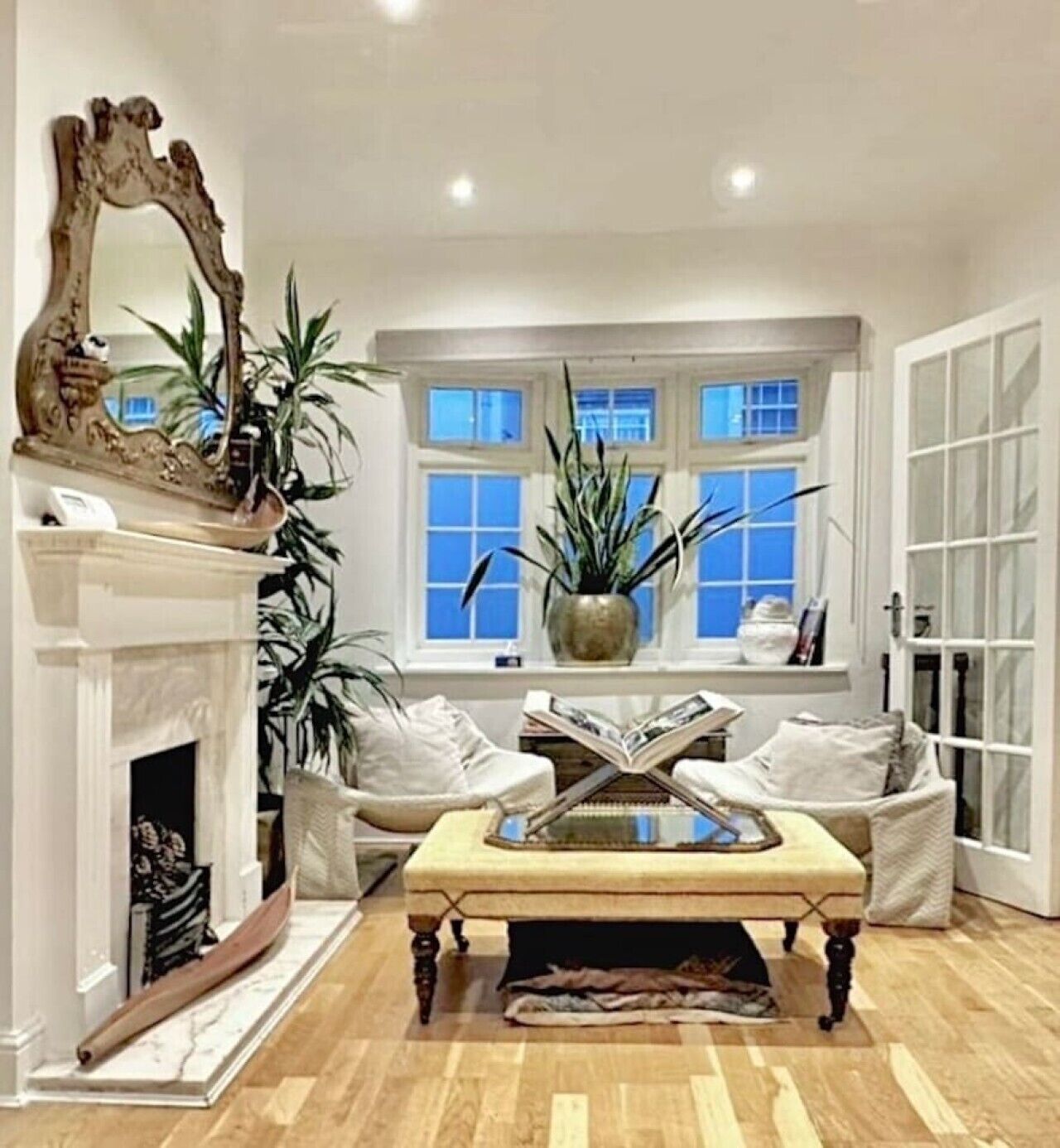 A living room with a fireplace, a sofa, a coffee table, and a large mirror.