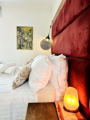 A bedroom with a red headboard, a bed with white bedding, a round lamp, and a painting on the wall. - Premier location for a london city-break (Greater London)