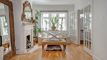 A spacious room with a fireplace, a large mirror, and a seating area with a table.
