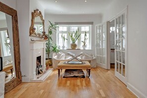 A spacious room with a fireplace, a large mirror, and a seating area with a table.