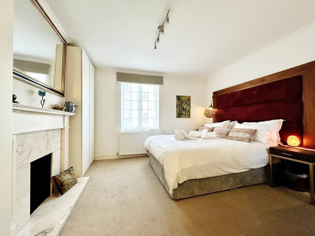 A bedroom with a bed, bedside table, and a fireplace.