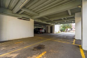 An underground parking garage with concrete pillars, a car parked in the distance, and yellow parking lines on the floor. - Palagan Huis (Ngaglik)