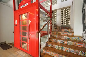 Una cabina telefónica roja con puerta de cristal, una escalera con azulejos de diseño colorido y una decoración interior moderna.