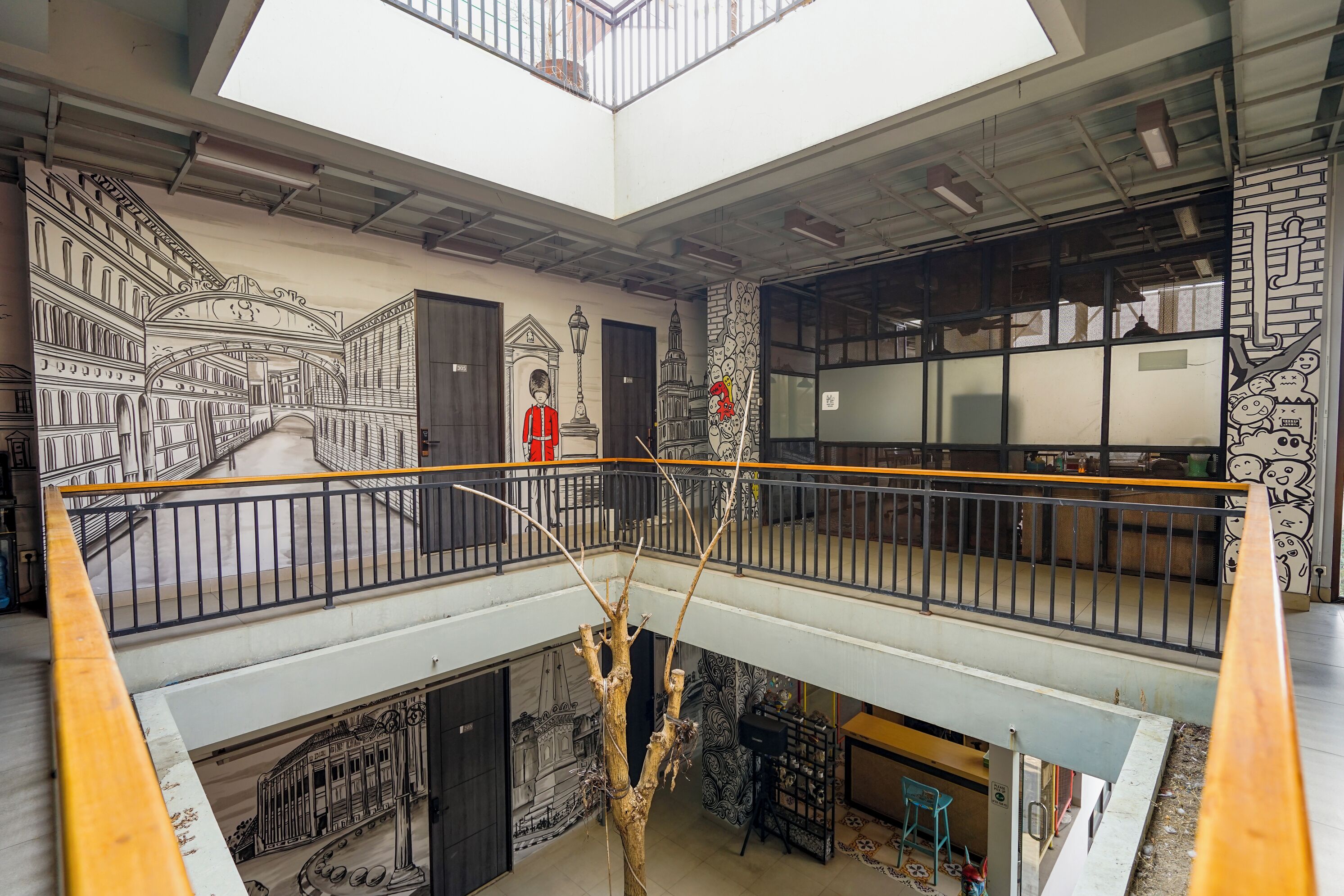 Un atrium à plusieurs niveaux, doté d’une verrière, d’un escalier et d’une fresque représentant un paysage urbain.