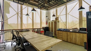 A conference room with a long table, chairs, and a kitchen area with cabinets and appliances.