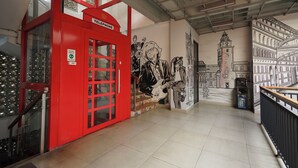 A red telephone booth with a mural of a cityscape and a clock tower.