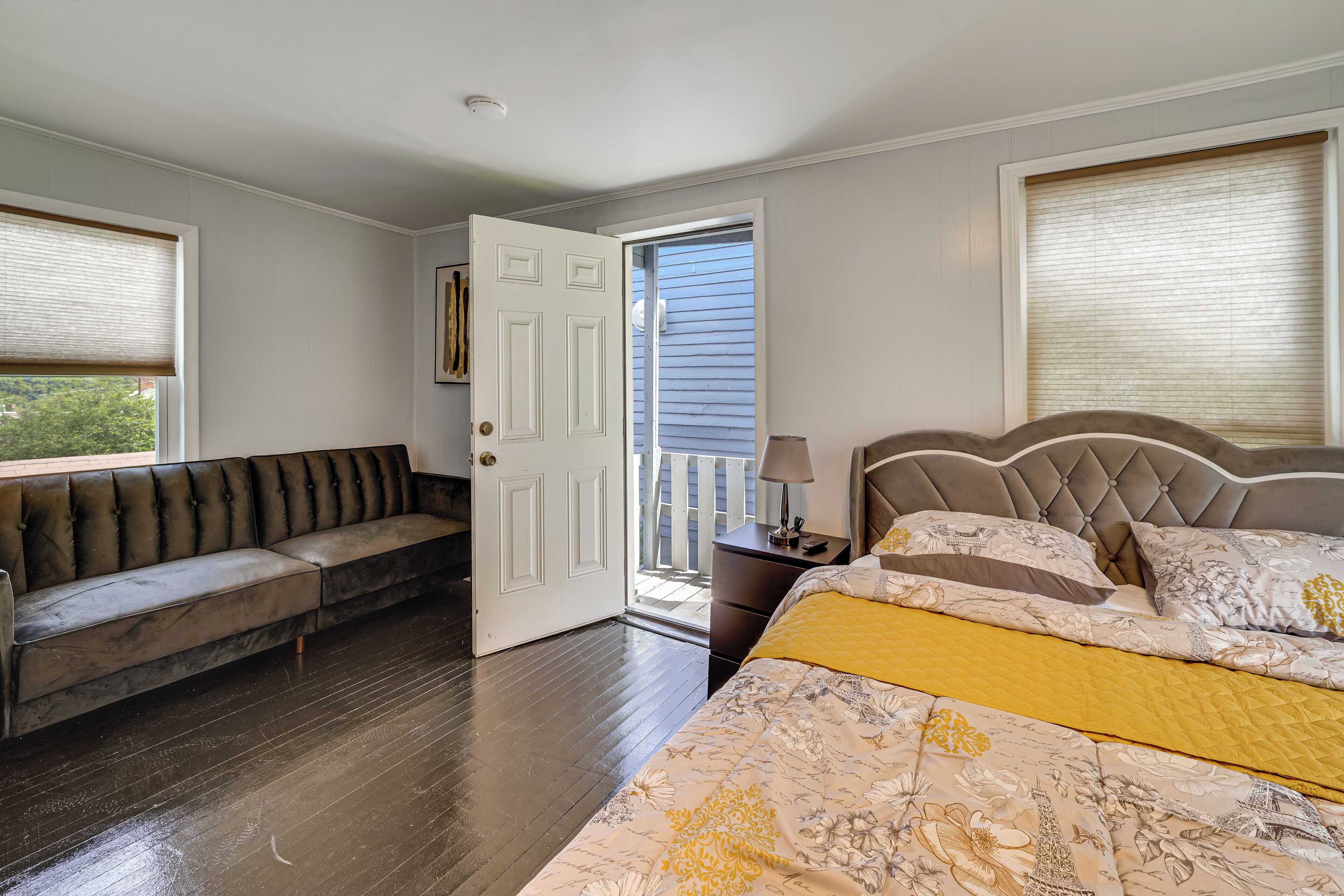 Un dormitorio con una cama, un banco, una mesita de noche y una puerta que da a un espacio exterior.