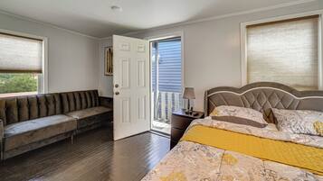 A bedroom with a bed, a bench, a nightstand, and a door leading to an outdoor area.