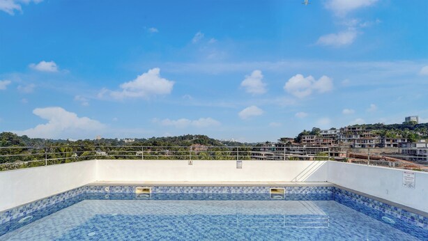 A rooftop swimming pool with a tiled floor and a clear view of the surrounding cityscape. - Super Collection O Kulathoor Technopark (Thiruvananthapuram)
