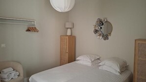 A bedroom with a bed, a hanging light fixture, a wardrobe, and a mirror on the wall. - Appartement Jehan de Beauce (Chartres)