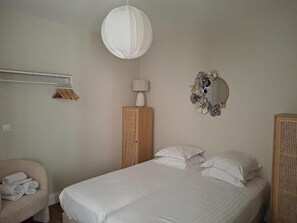 A bedroom with a bed, a hanging light fixture, a wardrobe, and a mirror on the wall. - Appartement Jehan de Beauce (Chartres)