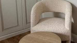 A room with a white wardrobe, a beige armchair, and a round wooden table. - Appartement Jehan de Beauce (Chartres)