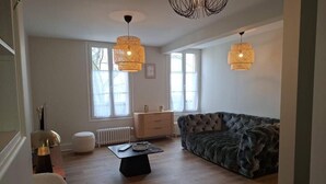 A living room with a sofa, a coffee table, and two pendant lights. - Appartement Jehan de Beauce (Chartres)