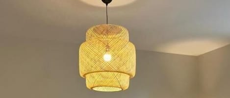 Uma sala de estar com televisão de tela plana, duas poltronas, uma mesa de centro e um lustre.