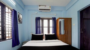 Un dormitorio con cama, armario, ventana con cortinas y aire acondicionado.