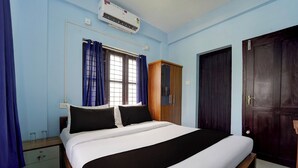 Un dormitorio con cama, armario, ventana con cortinas y aire acondicionado.