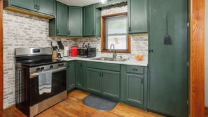 A kitchen with green cabinets, a stainless steel stove, a microwave, and a sink. - Peaceful Lake Getaway Near Bull Shoals Marina (Diamond City)