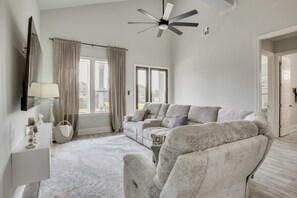 A spacious living room with a large sectional sofa, a ceiling fan, and a view of the outdoors through the windows. - 4 Mi to New Orleans! Extended Stay in Arabi (Arabi)