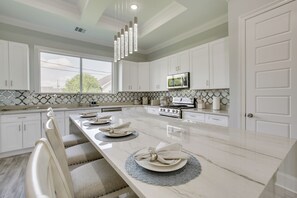 A modern kitchen with white cabinetry, a long island with a marble countertop, and a built-in microwave. - 4 Mi to New Orleans! Extended Stay in Arabi (Arabi)