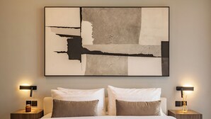 A neatly made bed with two pillows, a large abstract painting on the wall, and two bedside tables with lamps. - Elegant 2BR Private Pool Villa Umalas (Badung)