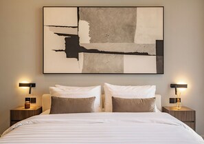 A neatly made bed with two pillows, a large abstract painting on the wall, and two bedside tables with lamps. - Elegant 2BR Private Pool Villa Umalas (Badung)