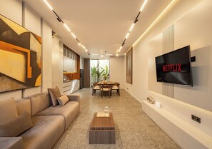 Un soggiorno moderno con un divano, un tavolino e una TV a parete.
