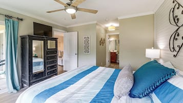 A bedroom with a bed, a ceiling fan, a wardrobe, and a bathroom visible through an open door.