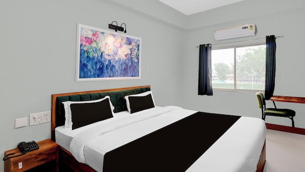A hotel room with a bed, a desk, an air conditioner, and a window with curtains. - Super Collection O Udaipur City (Udaipur)