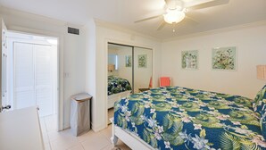 A bedroom with a bed, a ceiling fan, a mirror, and a door. - Walk to Beach! Old Naples Condo w/ Pool Access (Naples)