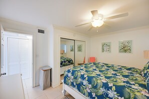 A bedroom with a bed, a ceiling fan, a mirror, and a door. - Walk to Beach! Old Naples Condo w/ Pool Access (Naples)