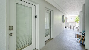 A corridor with two doors, a balcony with chairs, and a bike rack. - Walk to Beach! Old Naples Condo w/ Pool Access (Naples)