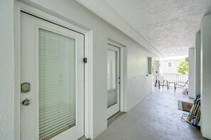 A corridor with two doors, a balcony with chairs, and a bike rack. - Walk to Beach! Old Naples Condo w/ Pool Access (Naples)