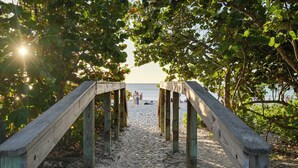A wooden pathway leading to a beach with people in the distance. - Walk to Beach! Old Naples Condo w/ Pool Access (Naples)