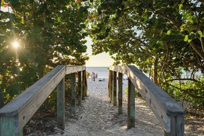 A wooden pathway leading to a beach with people in the distance. - Walk to Beach! Old Naples Condo w/ Pool Access (Naples)