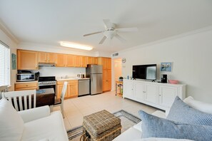 A compact living space with a kitchenette, a dining area, and a seating area with a television. - Walk to Beach! Old Naples Condo w/ Pool Access (Naples)