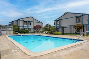 A rectangular swimming pool with a tiled edge, surrounded by lounge chairs and a fence. - Walk to Capitola Village: Condo w/ 2 Surfboards (Capitola)