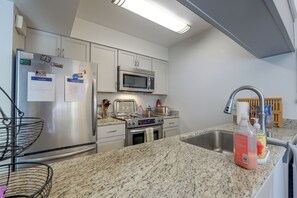 A modern kitchen with stainless steel appliances, a granite countertop, and a built-in microwave. - Walk to Capitola Village: Condo w/ 2 Surfboards (Capitola)