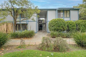 A two-story building with a covered entrance and a staircase leading to the upper floor. - Walk to Capitola Village: Condo w/ 2 Surfboards (Capitola)