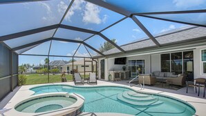 Piscina descoberta coberta com hidromassagem, espreguiçadeiras e área de estar com mobiliário para o exterior.