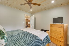 A bedroom with a bed, a wooden dresser, a television on top, and a ceiling fan. - Waterfront Stay w/ Dock & Views on Minong Flowage (Minong)