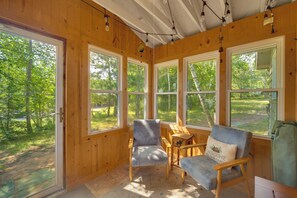 Eine Holzhütte mit großen Fenstern, Holzwänden und einer gemütlichen Sitzecke mit Stühlen und einem Tisch.