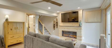 A living room with a grey sofa, a fireplace, and a ceiling fan.