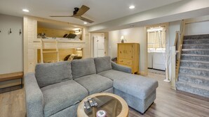 Una sala de estar con un sofá gris, un mueble de madera y un ventilador de techo.
