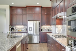 A modern kitchen with dark wood cabinets, stainless steel appliances, granite countertops, and a built-in oven. - Private Yard & Patio! Modern Manteca Gem (Manteca)
